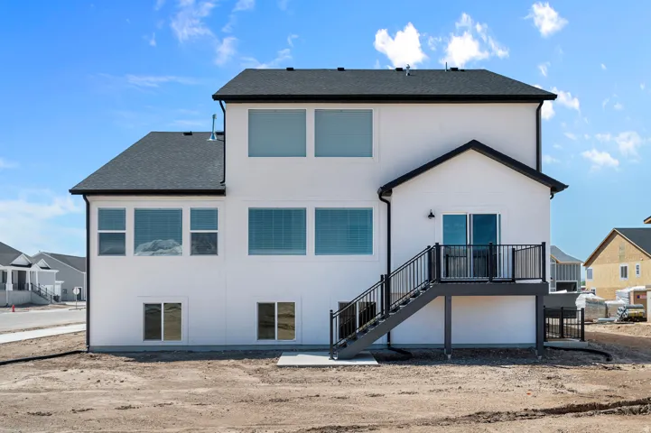 Rear exterior featuring white stucco siding, a multi-level deck with black railings, and multiple windows