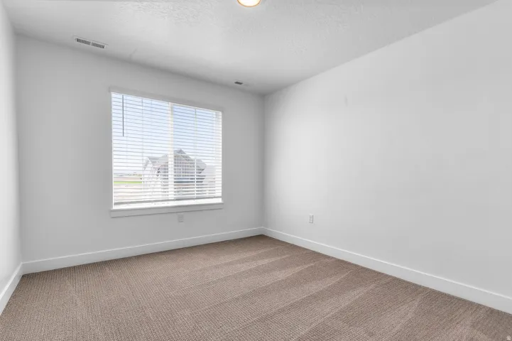Spacious room featuring neutral carpeting and white baseboards