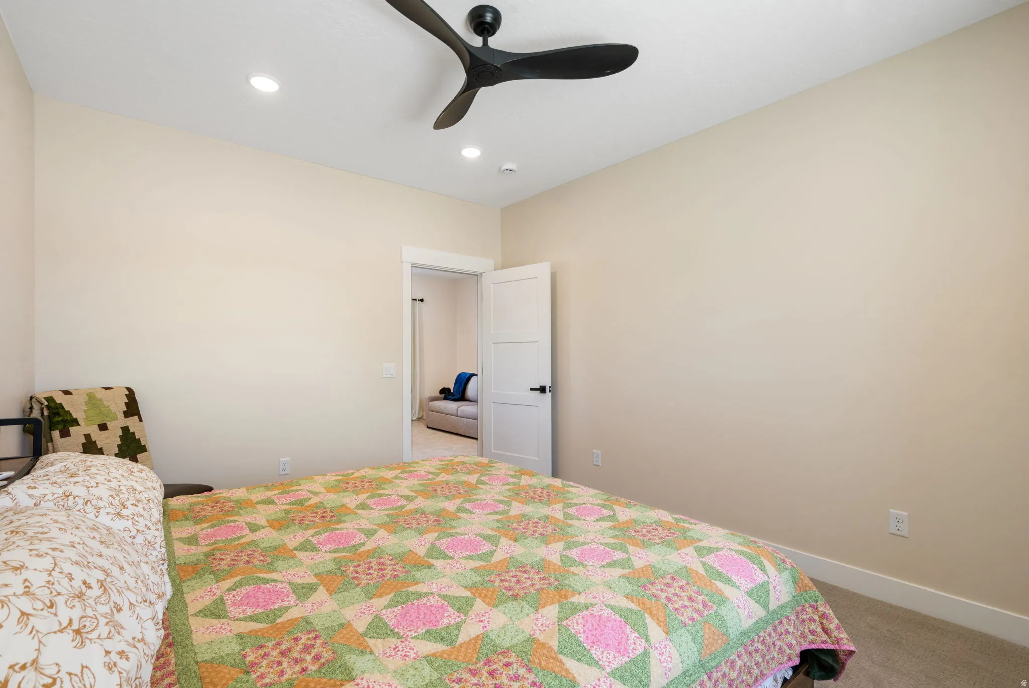 Carpeted room with neutral wall tones and a modern ceiling fan