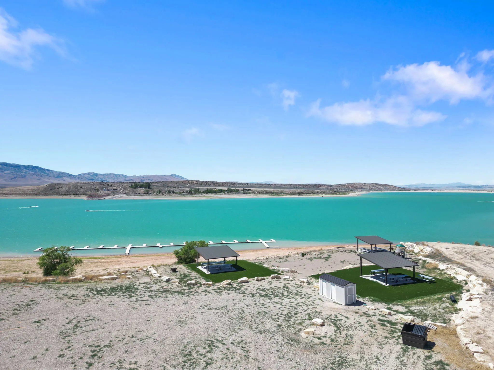 Waterfront property featuring a private dock, two covered patio structures, a storage shed, and a dedicated artificial turf area