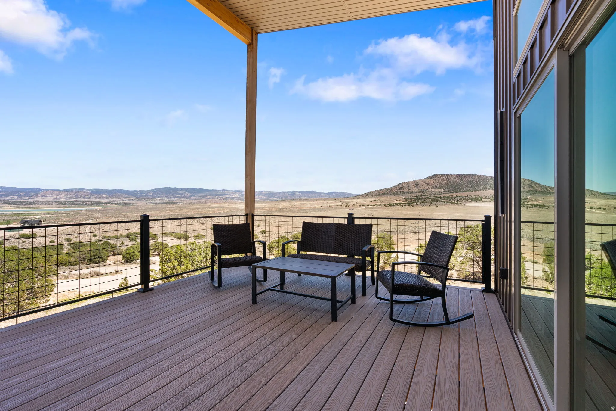 Expansive outdoor deck featuring wood-finish flooring, metal grid railing, and a covered ceiling