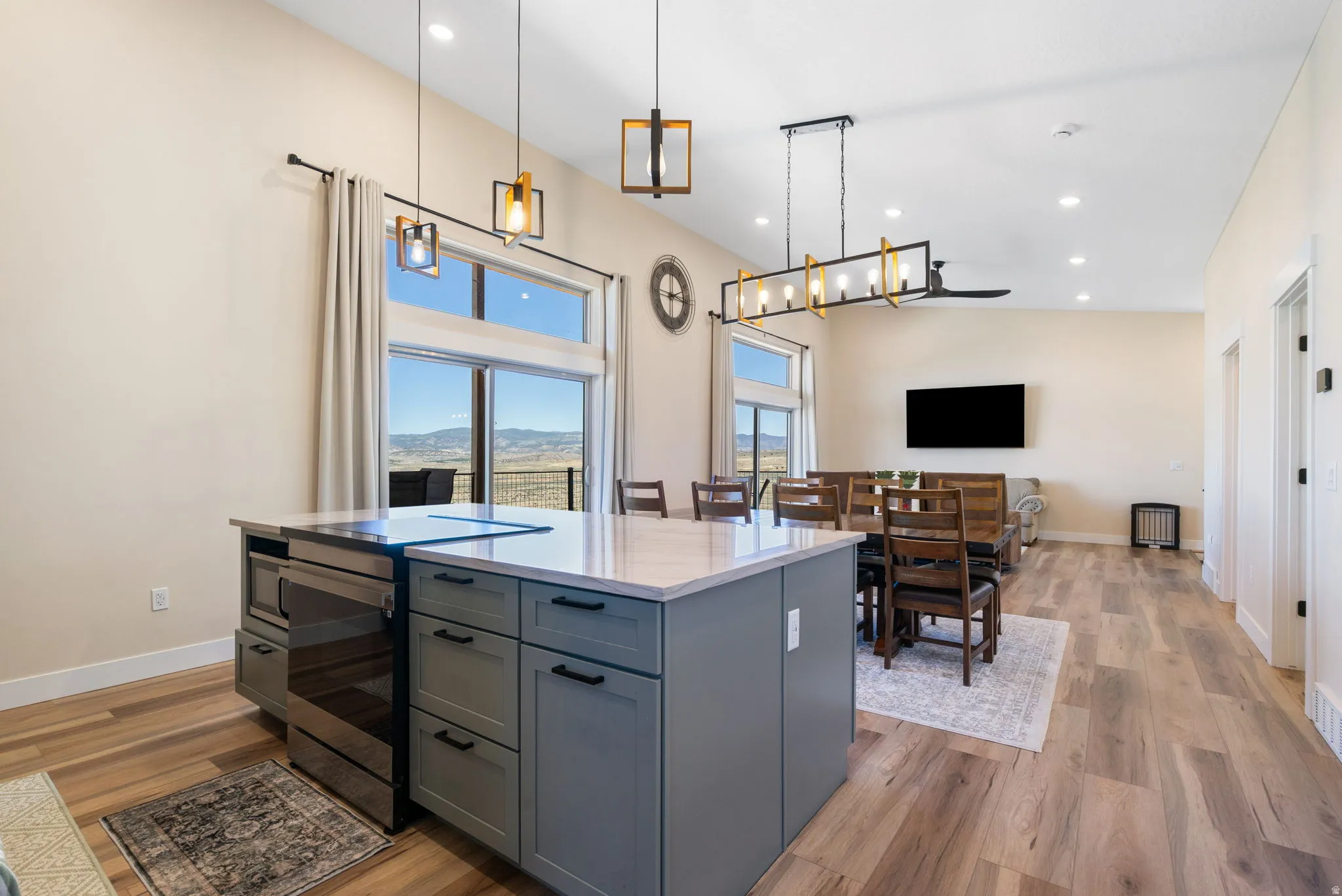 Open-concept living area featuring a kitchen island with gray cabinetry and a light-toned countertop