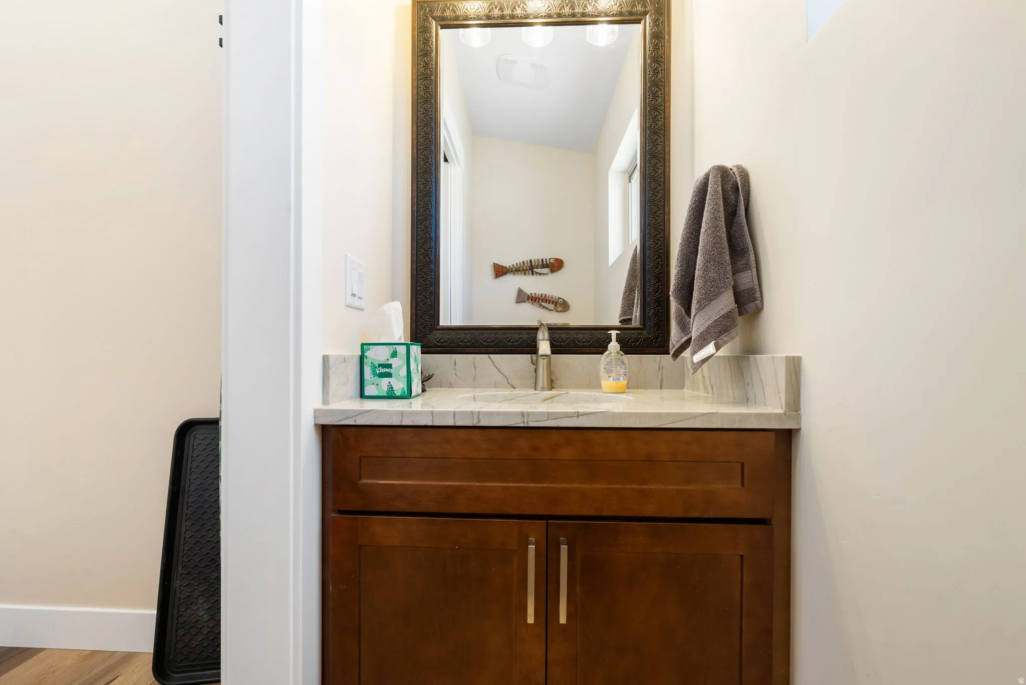 Bathroom vanity featuring a wood-finish cabinet, brushed nickel hardware, and a light-toned countertop