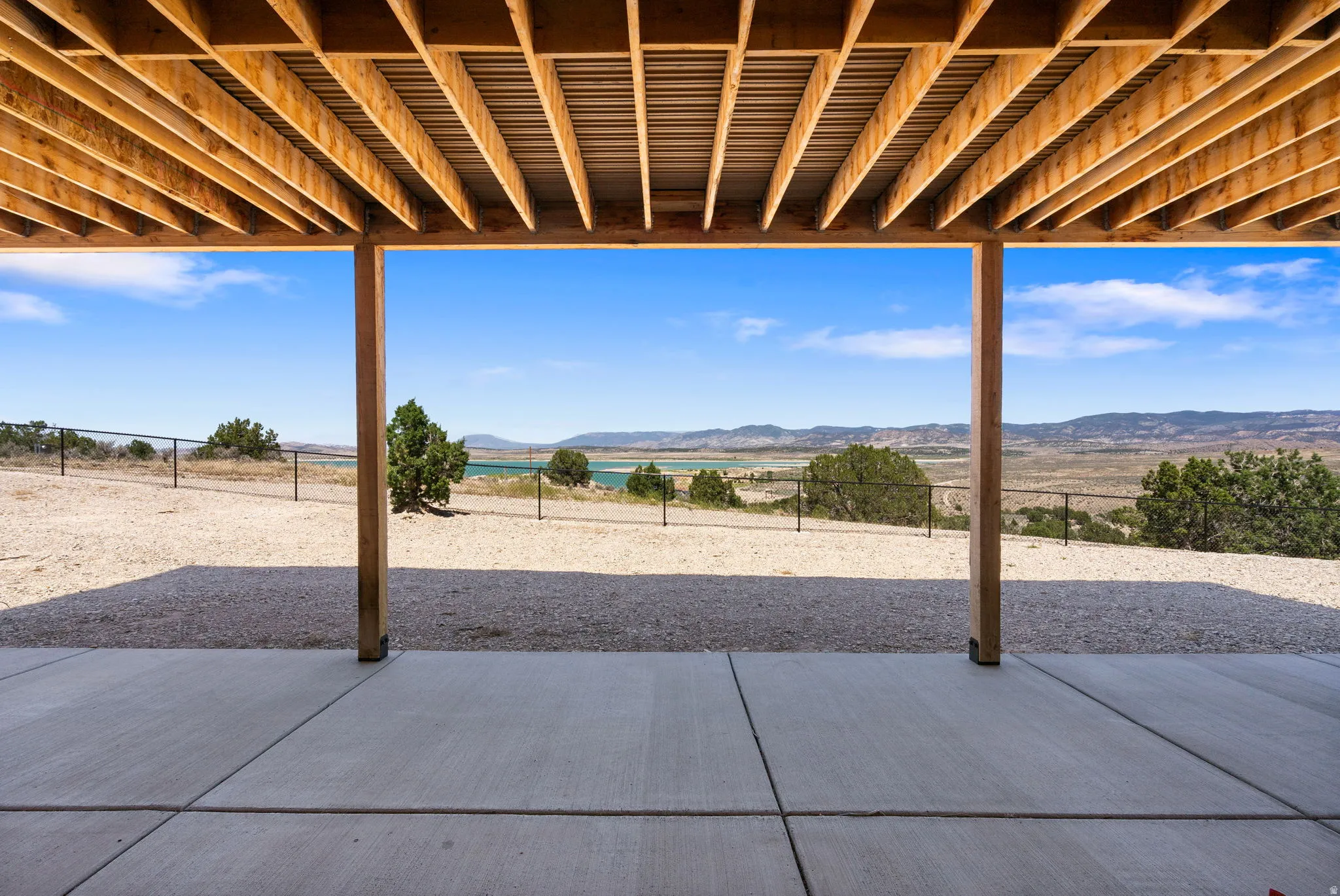 Covered patio with a concrete surface, supported by exposed wood beams and posts