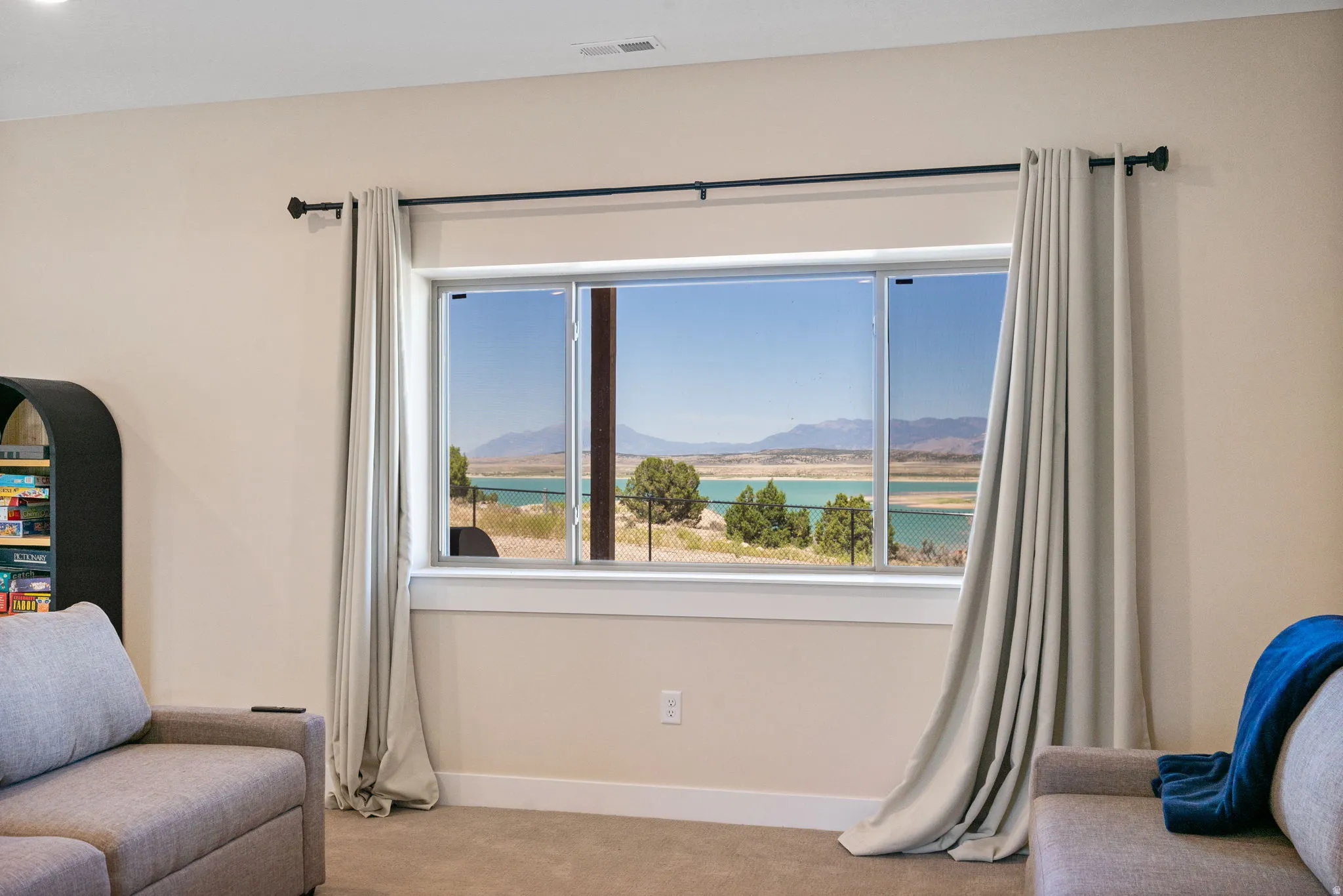 Expansive picture window framing a prominent water body and distant mountains