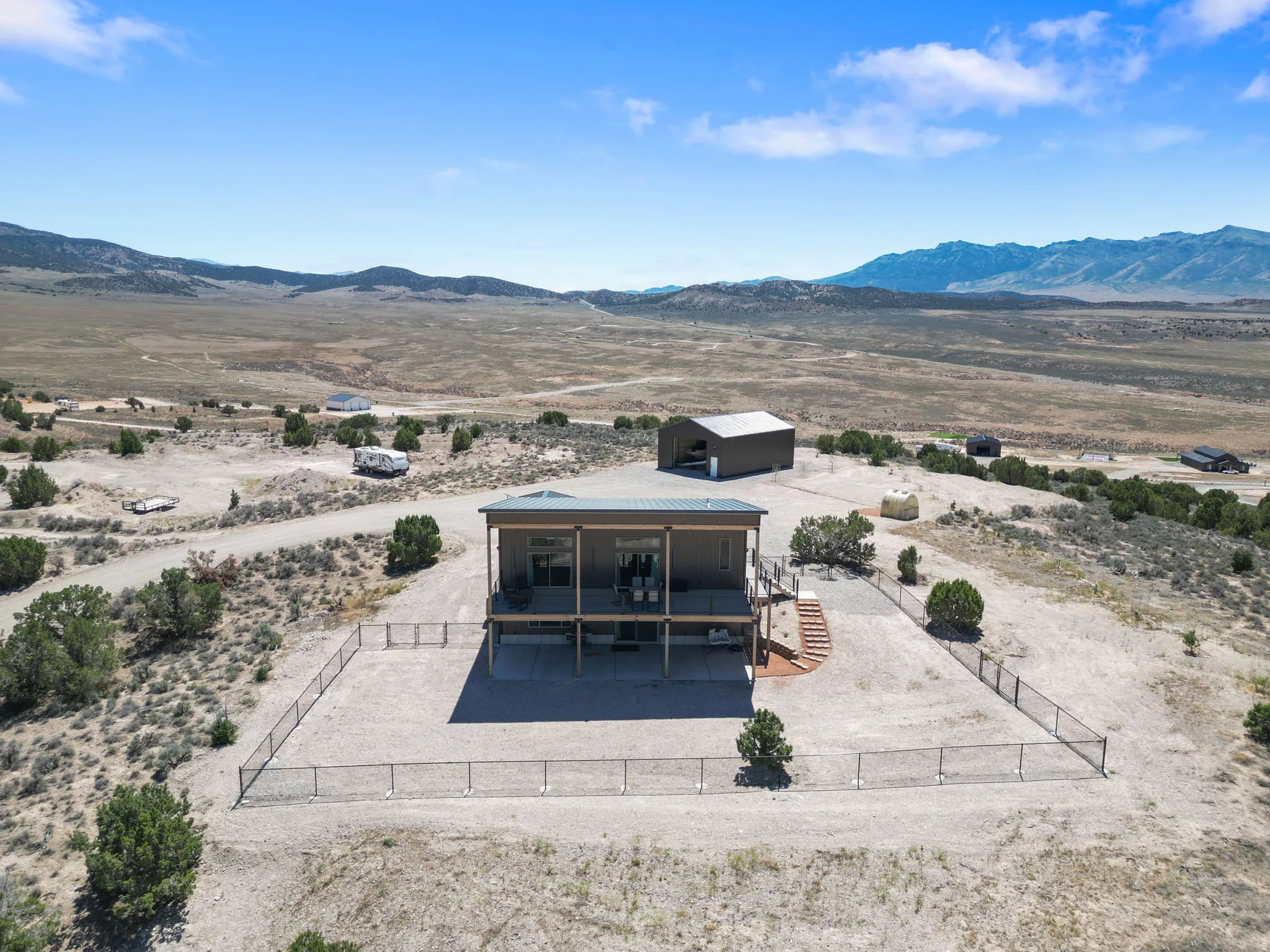 Elevated property featuring a covered deck, lower patio, and a separate metal storage building