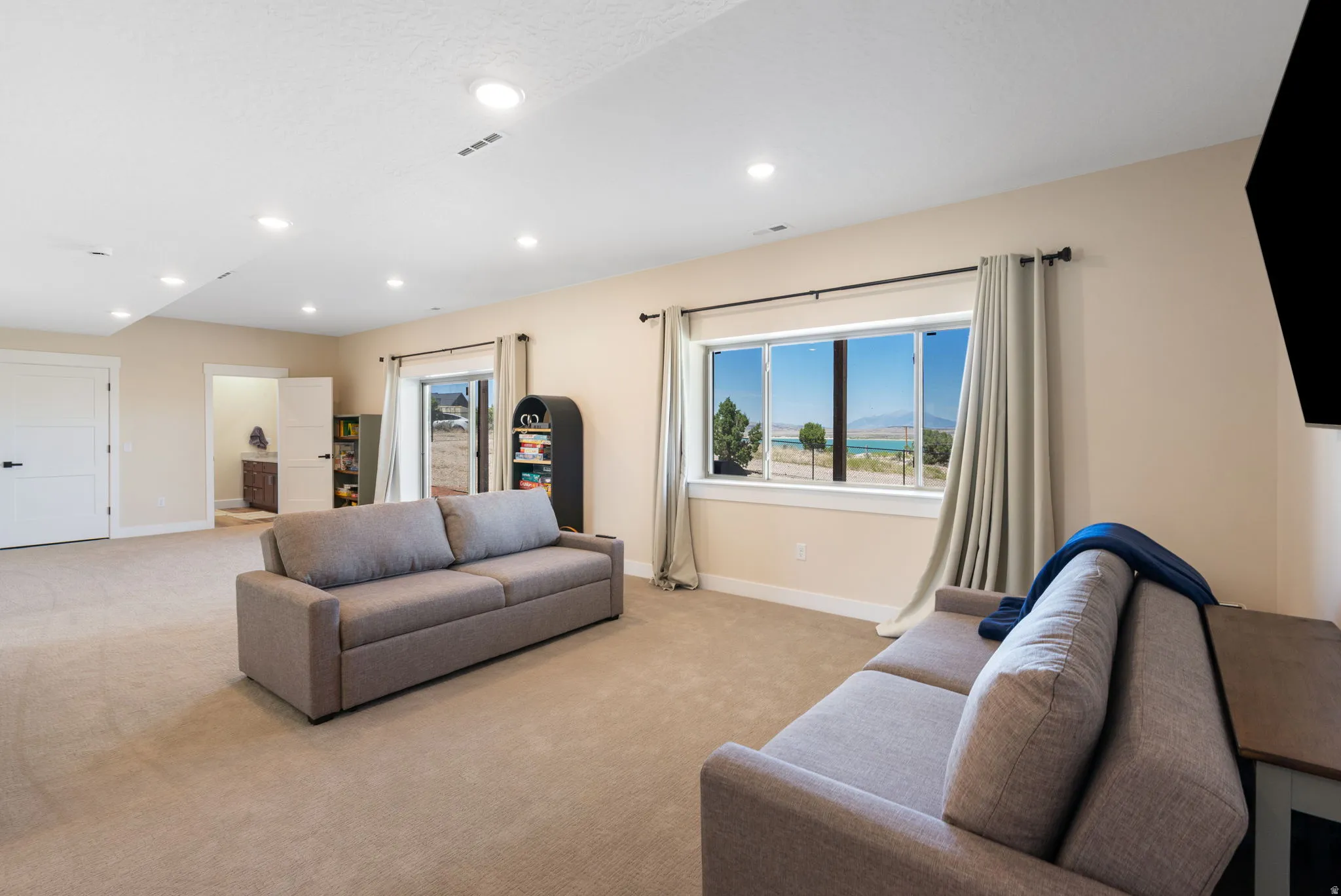 Spacious lower-level room featuring light-toned carpeting and recessed lighting