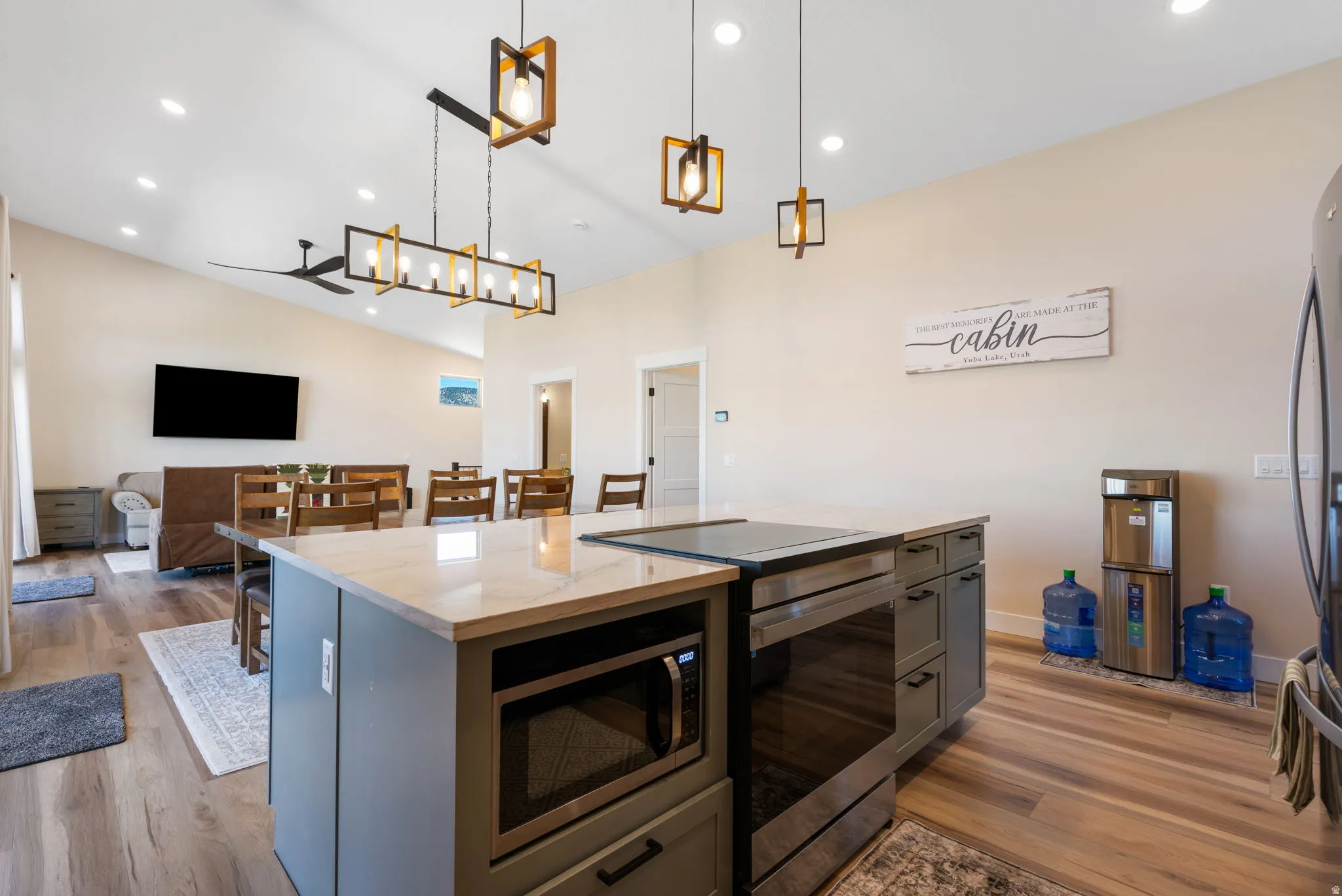 Open-concept kitchen and living area featuring a central island with integrated microwave, a built-in oven, and a flat cooktop