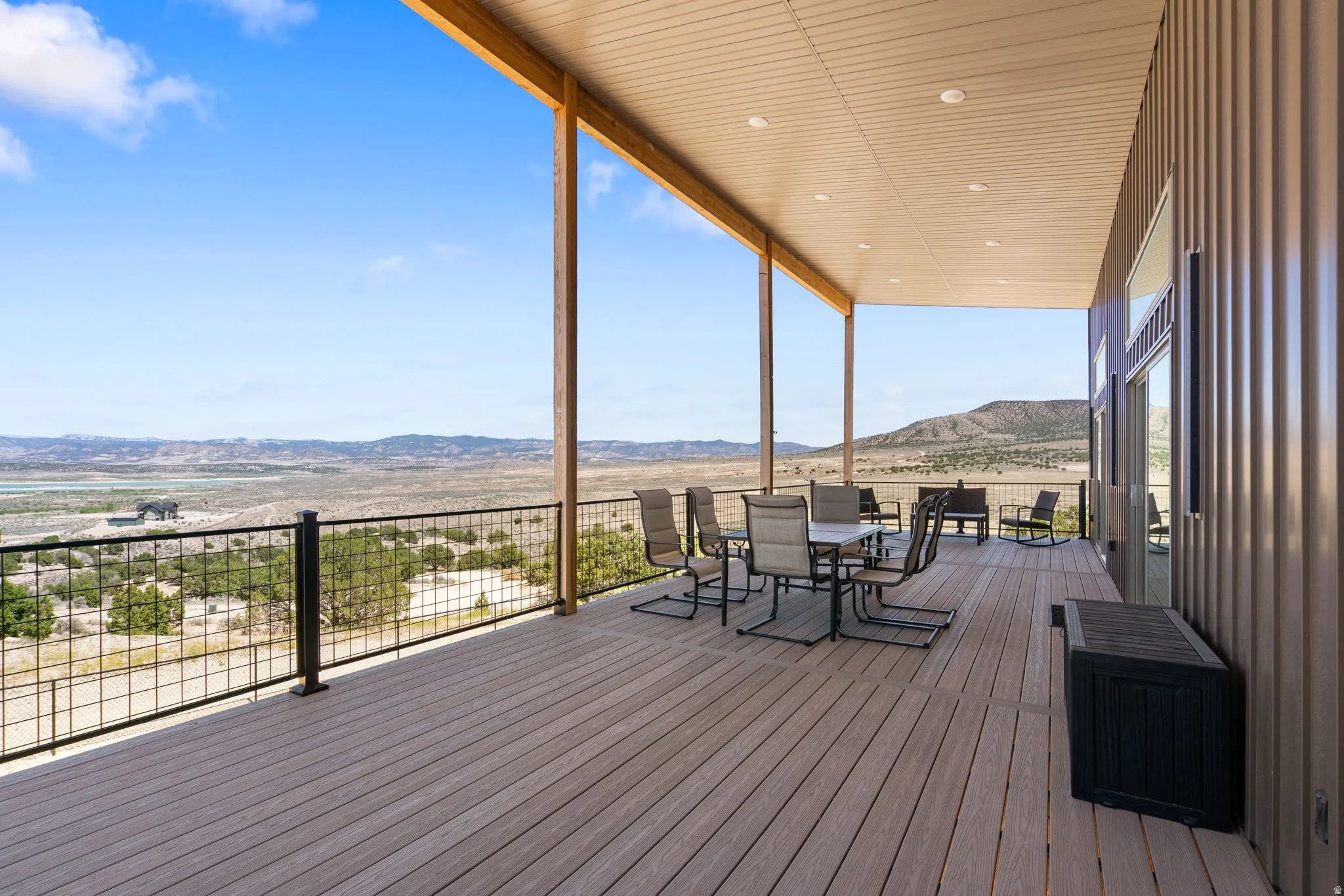 Expansive covered deck featuring wood-finish flooring and a black metal grid railing