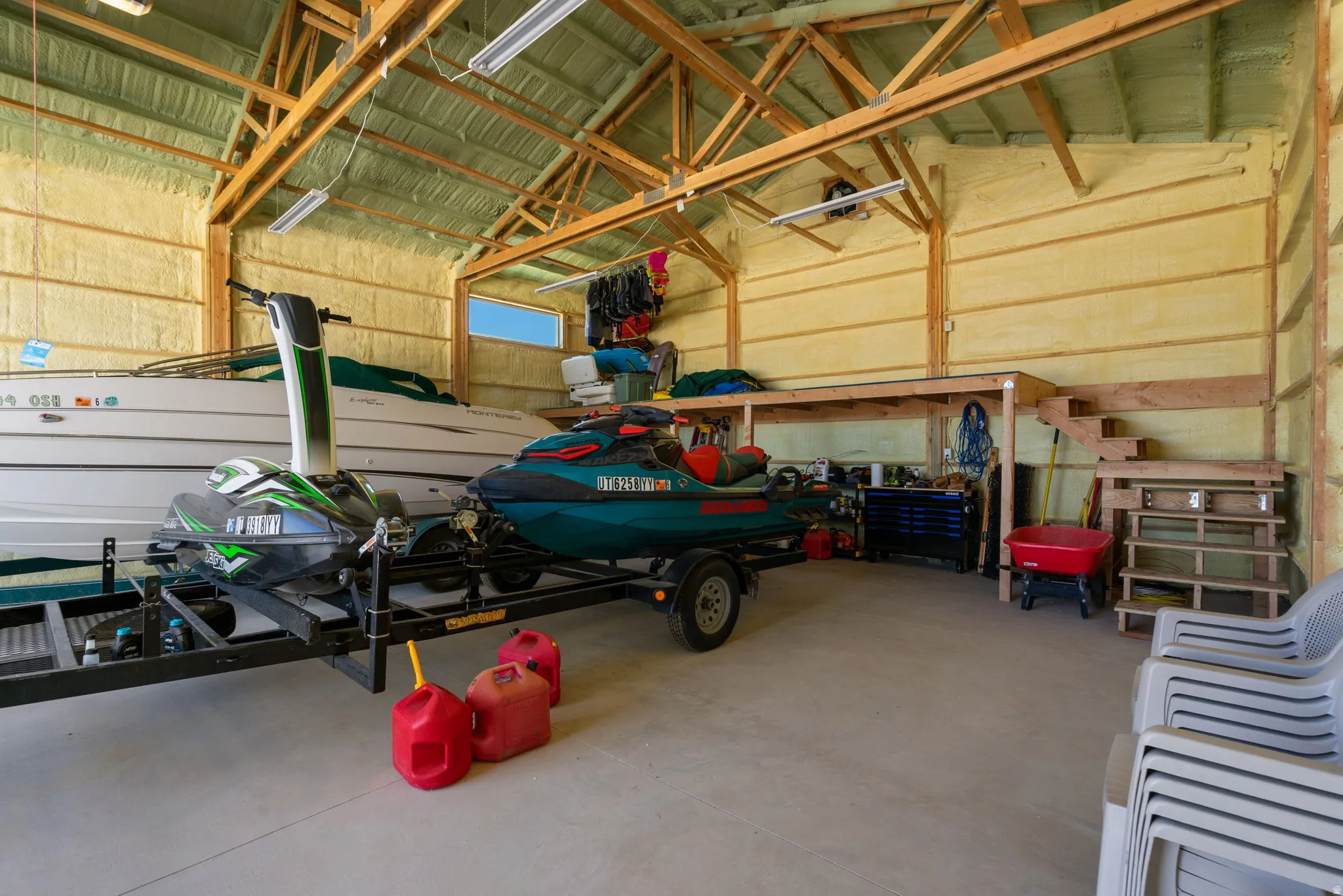Spacious utility building featuring a concrete floor, exposed wood beam ceiling, spray foam insulation, a built-in loft, and a window for natural light