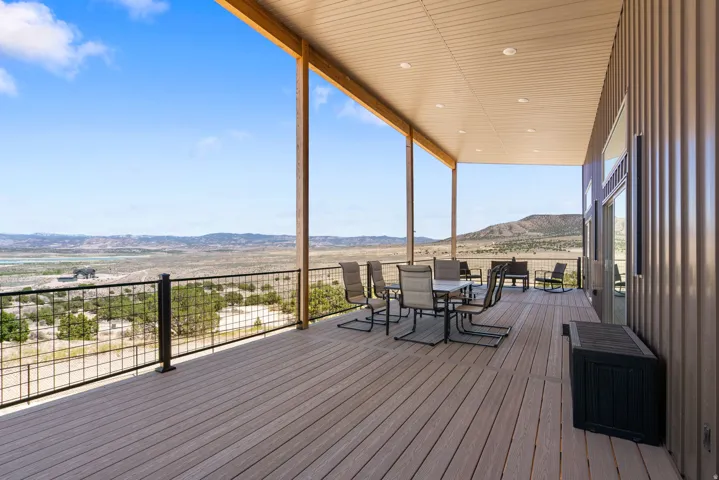 Expansive covered deck featuring wood-finish flooring and a black metal grid railing