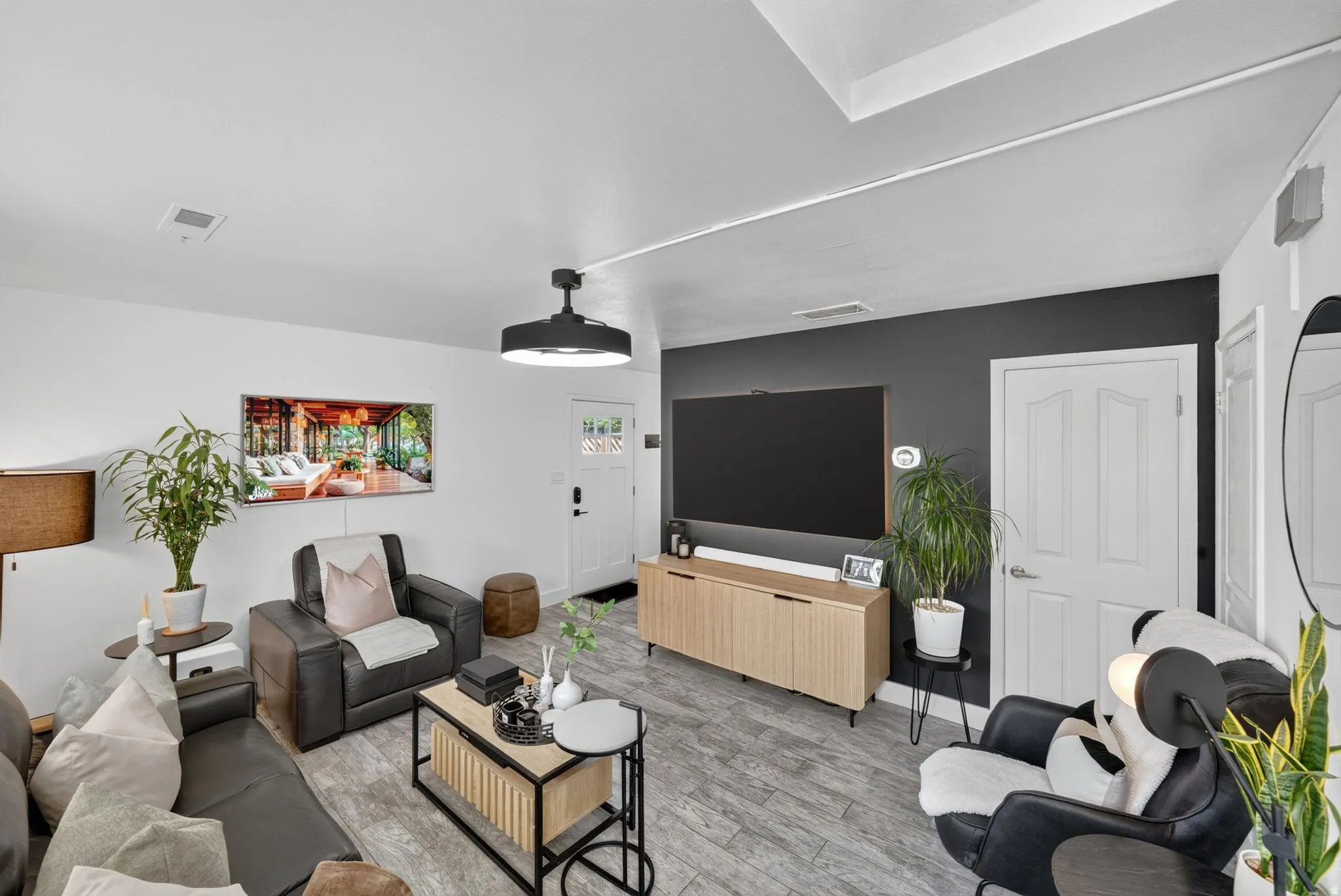 Living area featuring light wood-finish flooring, white walls, and a contrasting accent wall