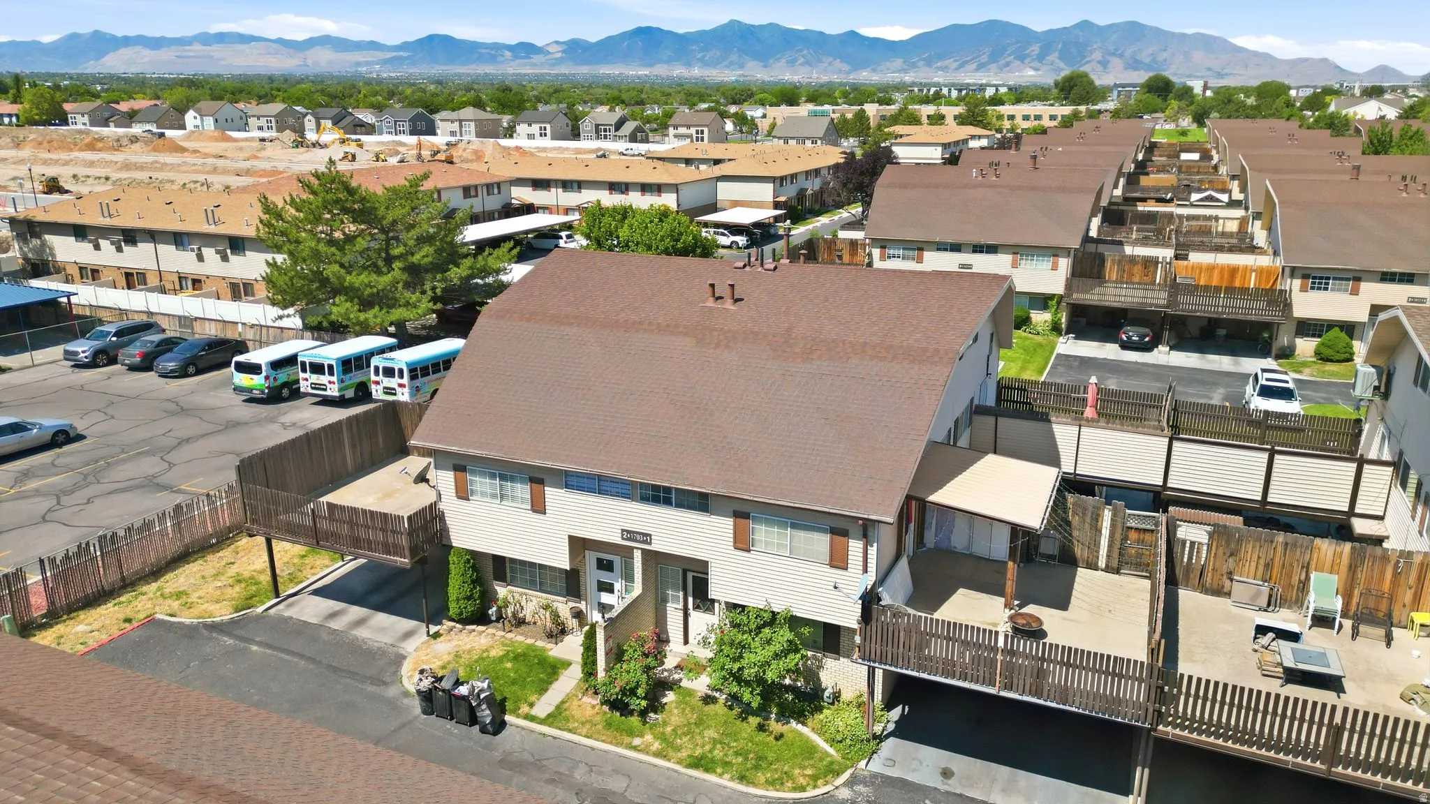 Multi-level residential building featuring a brown shingle roof, light-colored siding, and brown window shutters