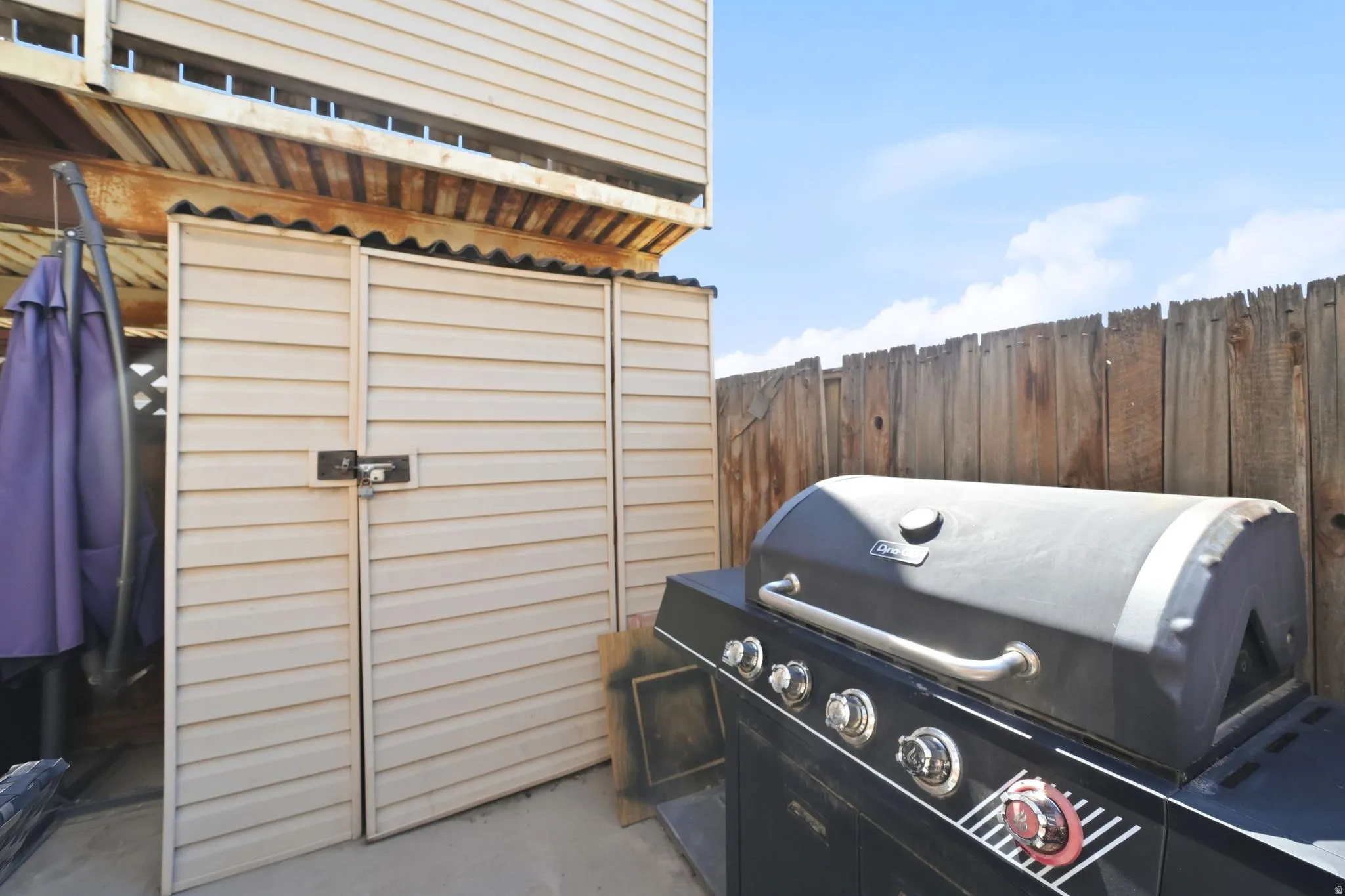 Outdoor storage shed with louvered doors and a wood fence boundary