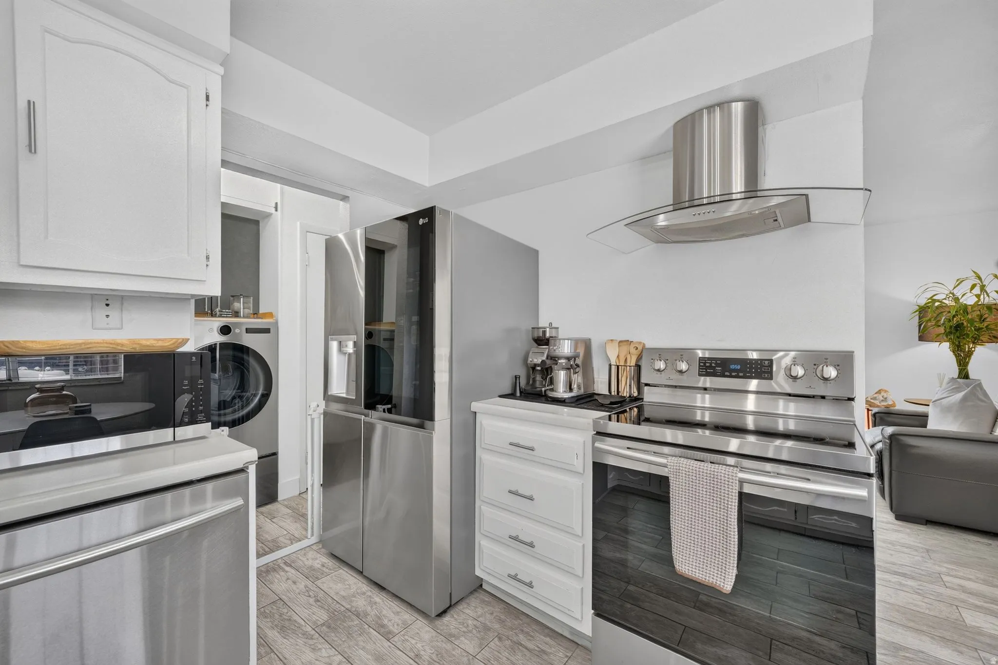 White kitchen cabinetry with stainless steel appliances, including a refrigerator, range, and microwave