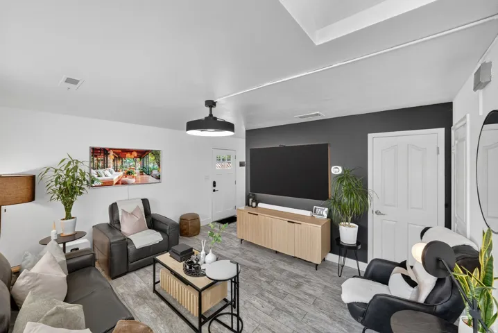 Living area featuring light wood-finish flooring, white walls, and a contrasting accent wall
