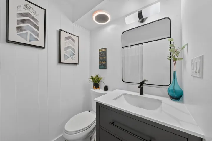 Modern bathroom featuring a dark vanity with a white countertop and integrated sink