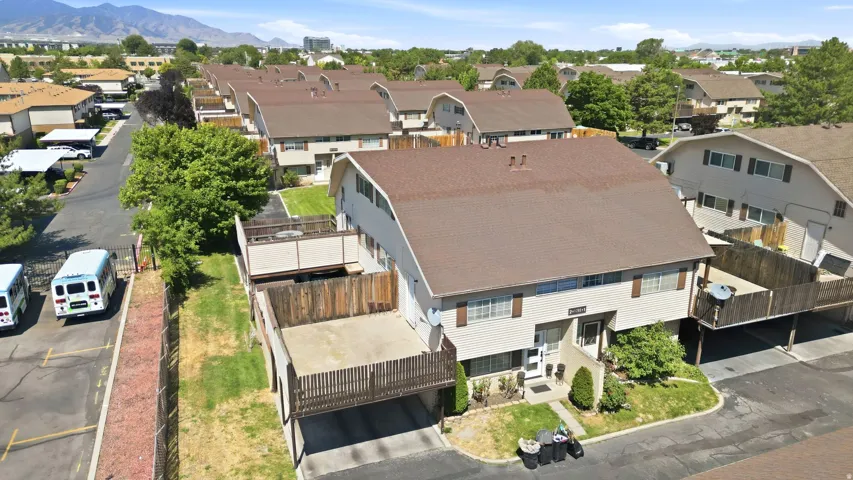 Two-story townhome with a brown shingle roof, light-colored siding, and dark window shutters