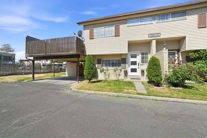 Exterior features include tan siding, a white entry door with frosted glass panels, and a carport