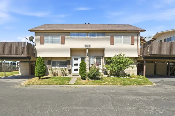 Two-story multi-unit property featuring light-colored siding and a brown shingle roof