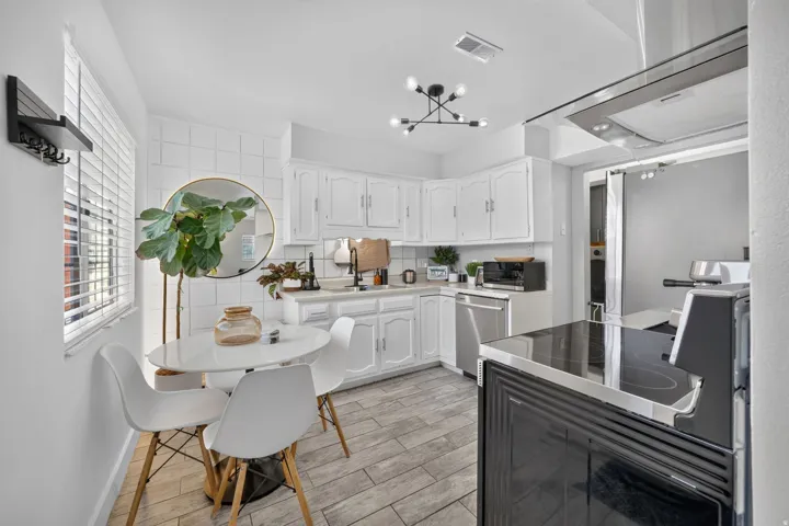 Bright kitchen featuring white cabinetry, light countertops, and a full suite of stainless steel appliances including a built-in dishwasher and range hood