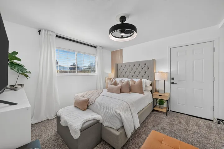 Carpeted room featuring a ceiling-mounted fan, a paneled door, and a window with horizontal blinds