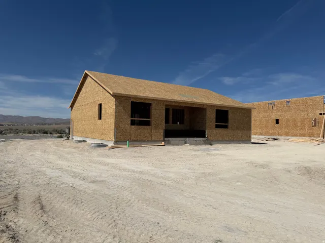 Newly framed single-story residence under construction, featuring a gabled roofline and a foundational concrete perimeter