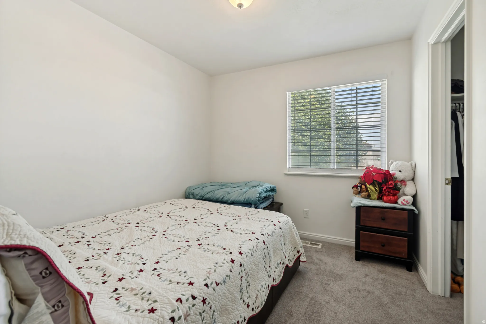 Bedroom featuring neutral wall paint, gray carpeting, a window with blinds, and an adjacent closet