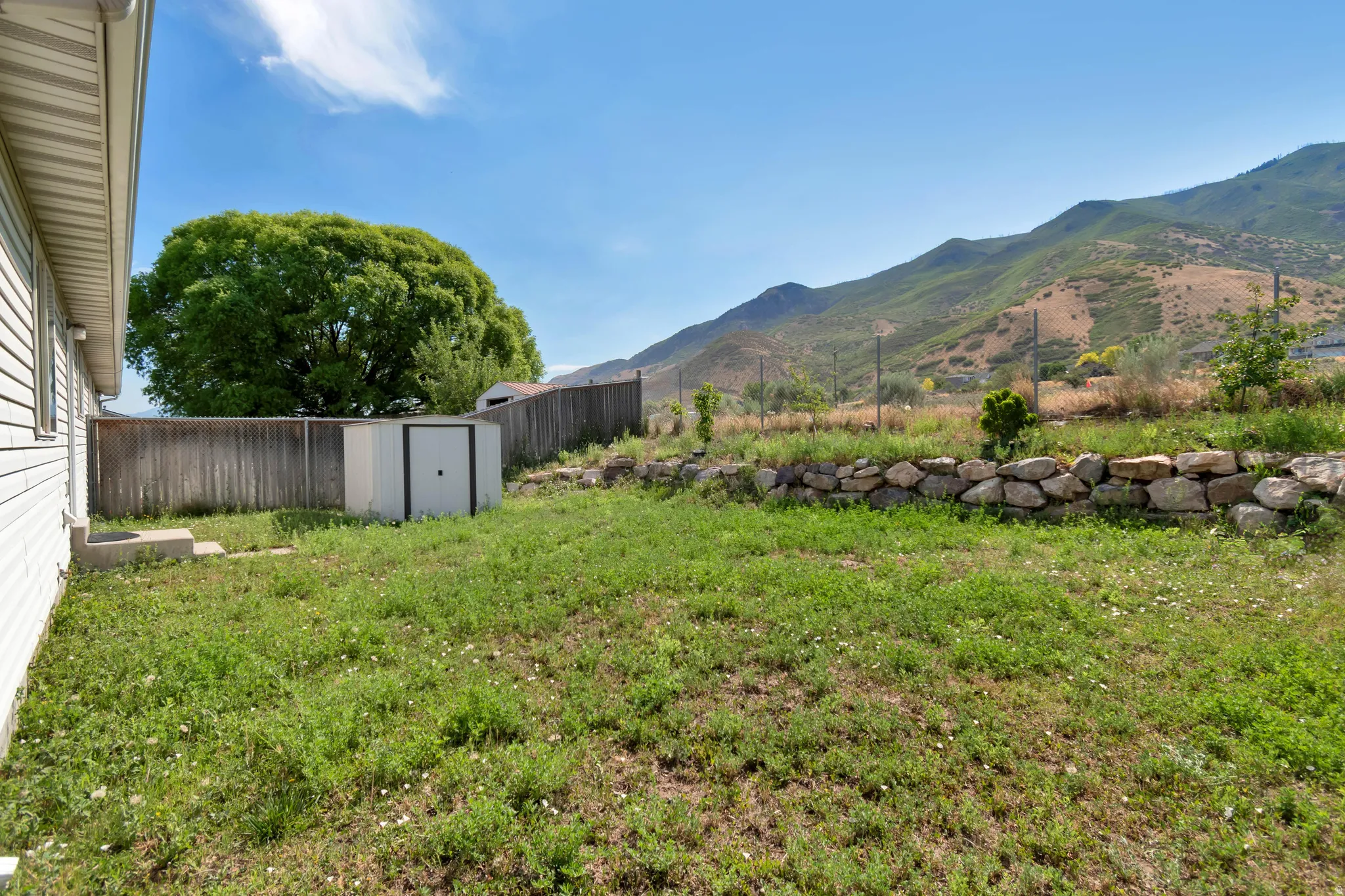 Expansive backyard featuring a natural stone retaining wall and mountain backdrop