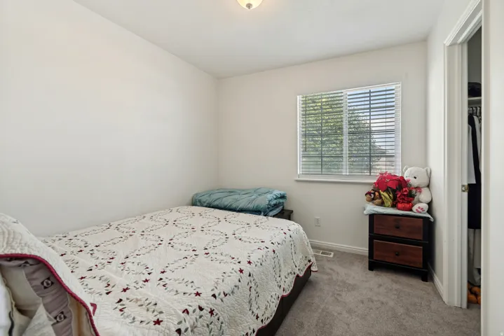 Bedroom featuring neutral wall paint, gray carpeting, a window with blinds, and an adjacent closet