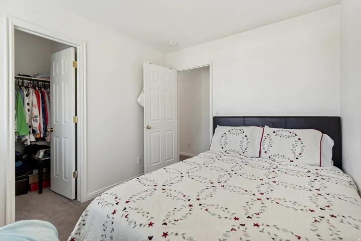 Bedroom featuring light neutral wall paint, carpet flooring, and a walk-in closet with a bi-fold door and interior shelving