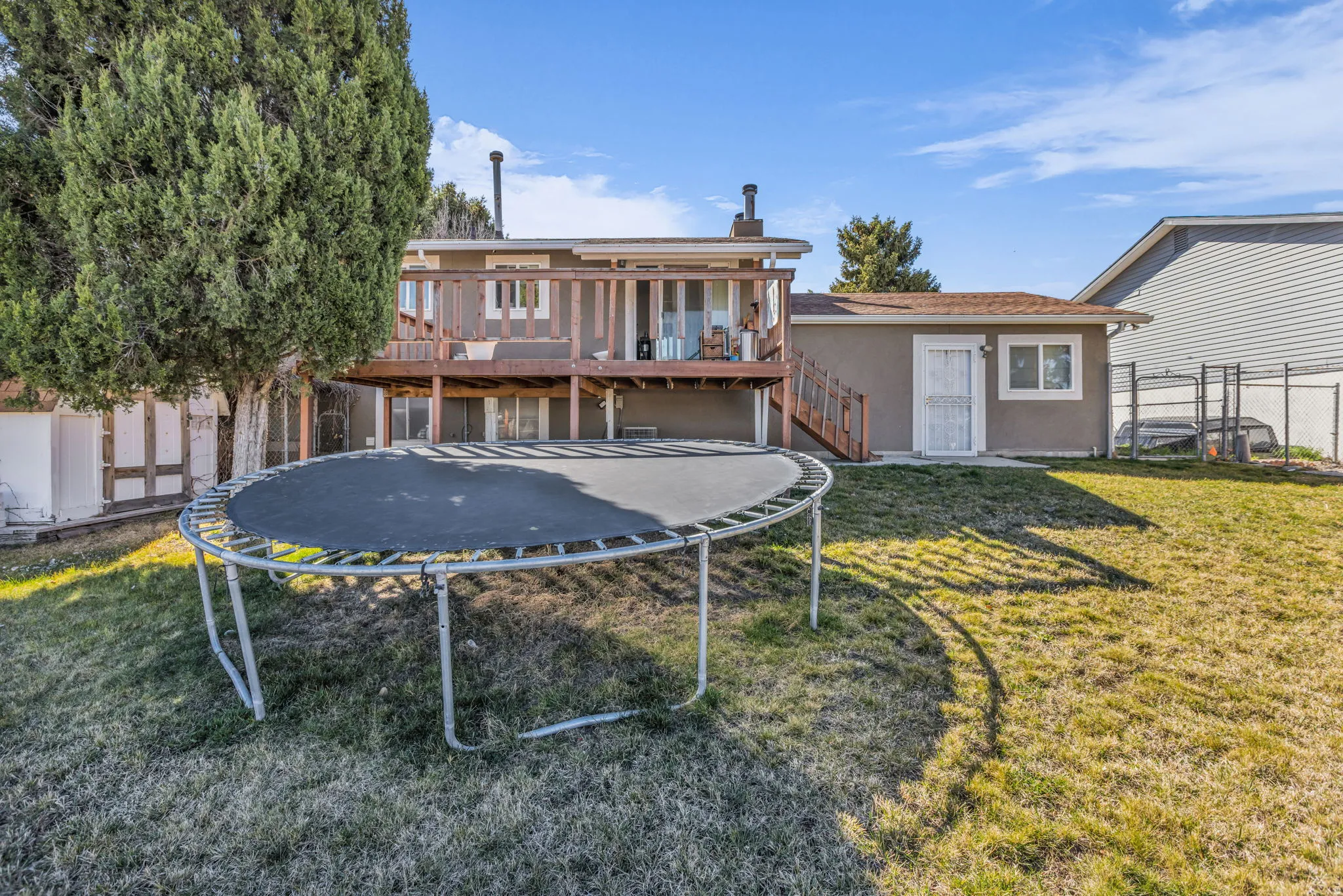 Expansive backyard featuring a multi-level deck, lower patio access, and a separate structure with exterior access
