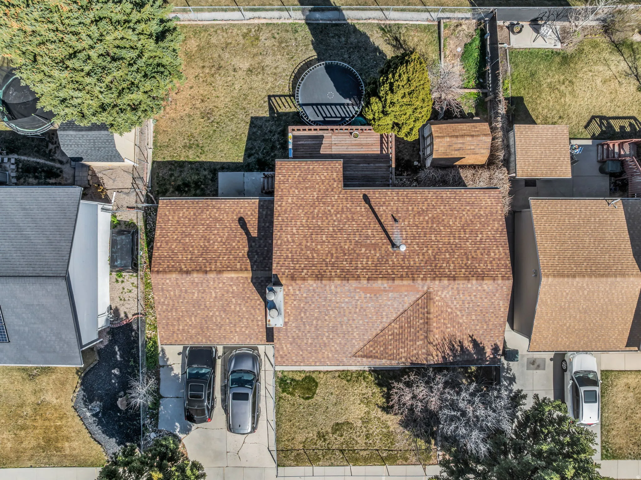 Property featuring a brown shingle roof, rear deck, and two storage sheds