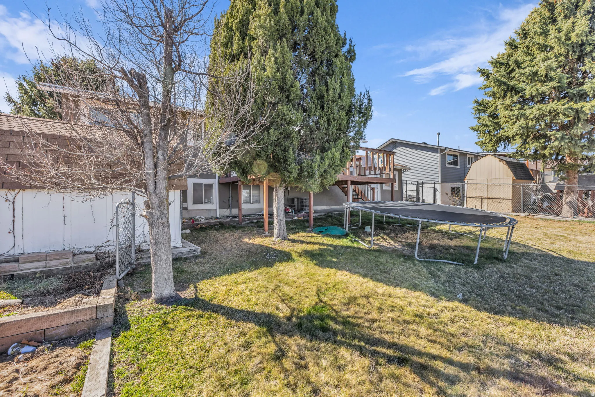 Expansive rear yard featuring green lawn, mature trees, and a multi-level deck structure with wood railings