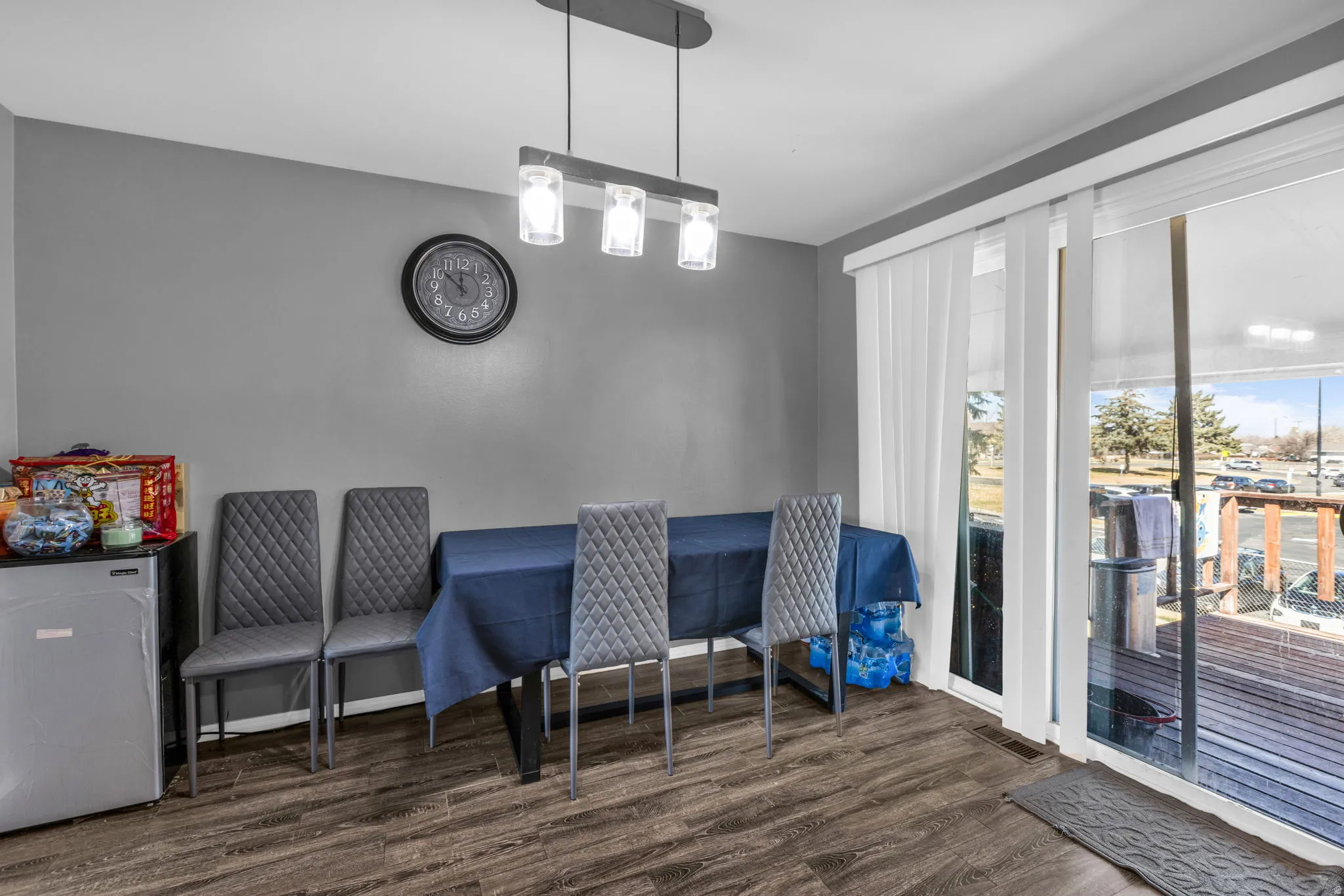 Dining area featuring wood-finish flooring, a modern linear pendant light fixture, and a sliding glass door providing exterior access