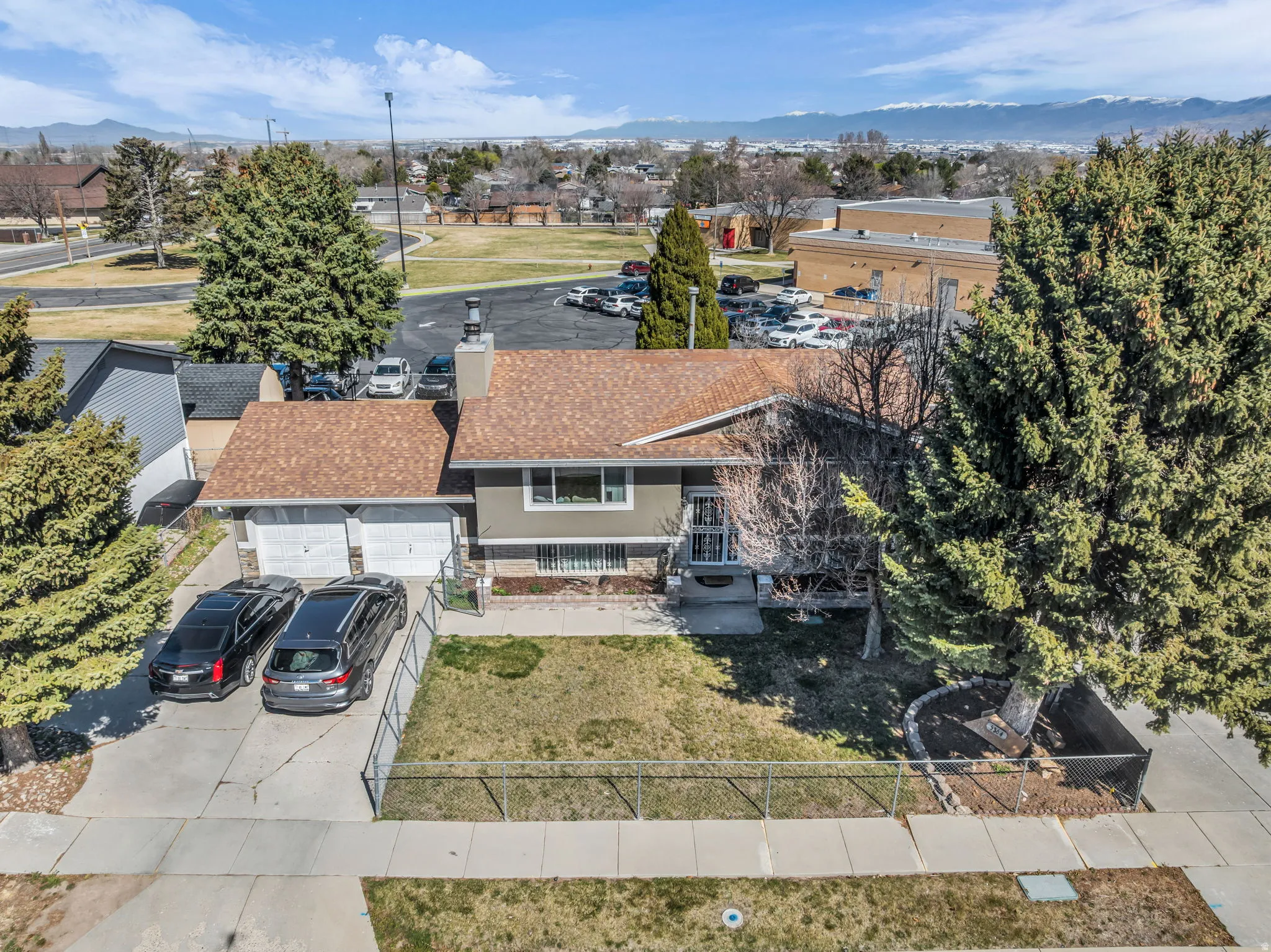 Split-level residence featuring a two-car garage, mature front yard trees, front lawn area, and a paved driveway
