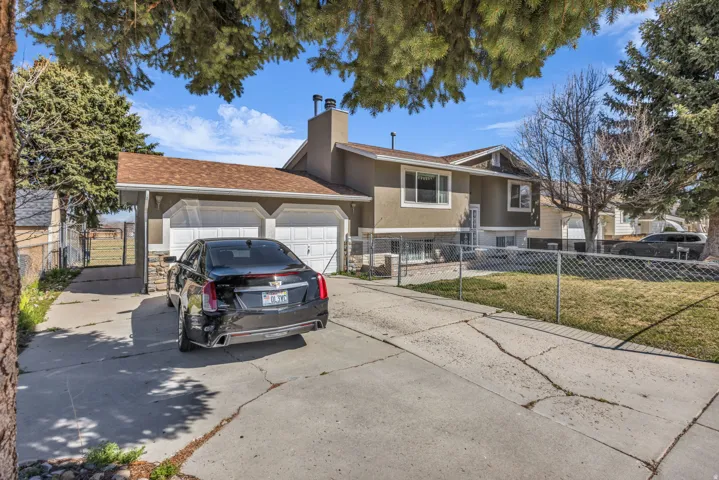 Split-level residence featuring a two-car garage with white panel doors and a shingle roof