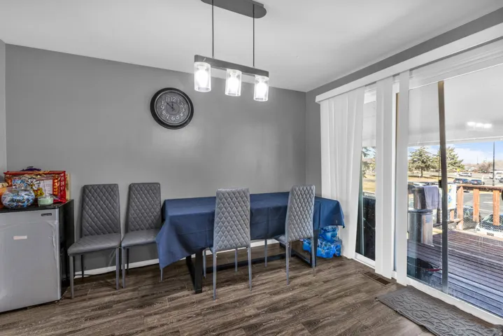 Dining area featuring wood-finish flooring, a modern linear pendant light fixture, and a sliding glass door providing exterior access