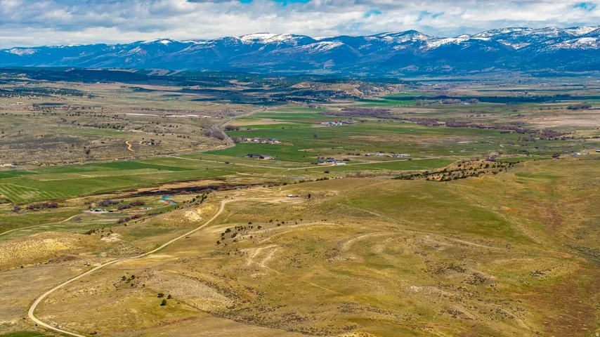 Expansive landscape featuring rolling hills and distant snow-capped mountains