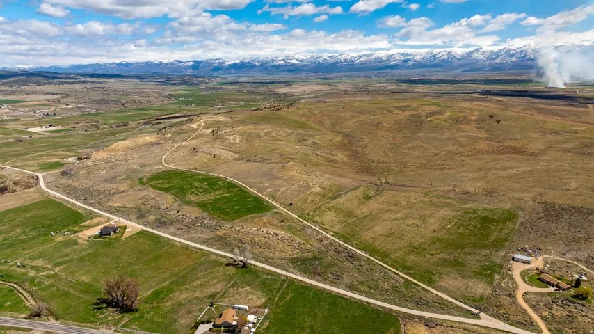 Expansive rural landscape featuring a mix of green fields and arid terrain, with visible access roads