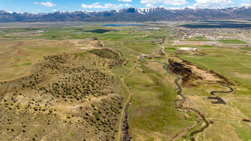 Expansive land parcel featuring varied topography, a meandering river, and distant snow-capped mountains