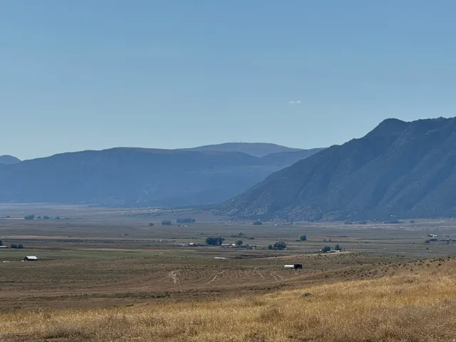 Expansive open landscape featuring distant mountains and scattered structures