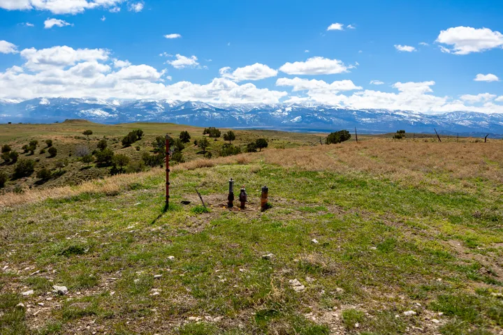 Expansive undeveloped land featuring natural grasses, scattered shrubbery, and distant snow-capped mountains