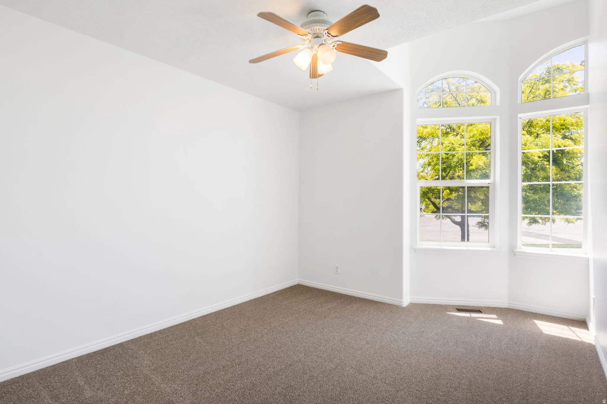 Spacious room featuring a vaulted ceiling and a ceiling fan with integrated lighting