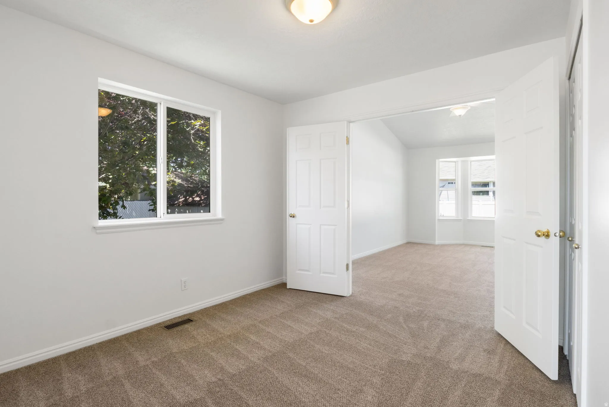 Neutral tone carpeting extending throughout, crisp white walls and trim, and a window with a white frame