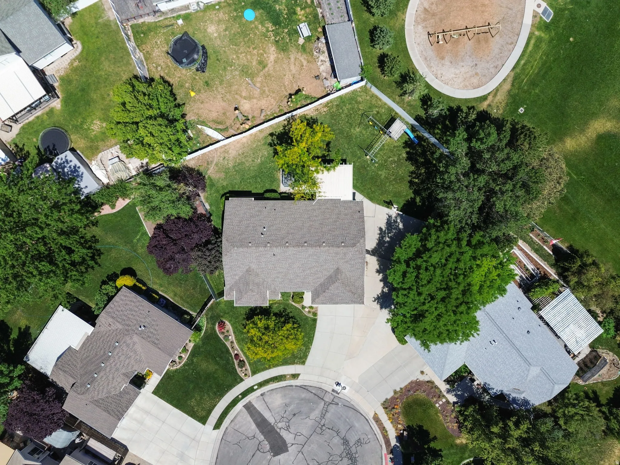 Aerial perspective showcasing a property with a grey shingle roof and a concrete driveway