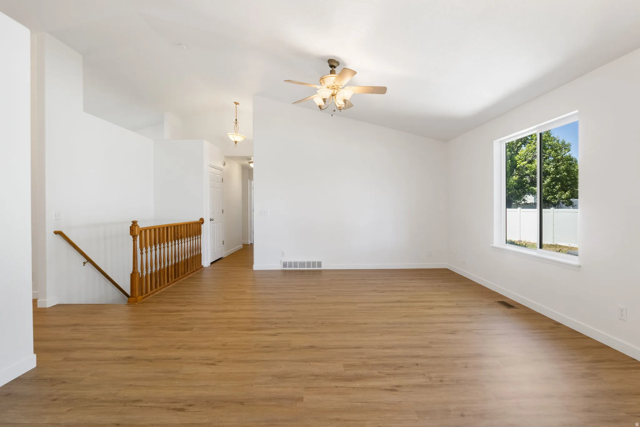 Spacious living area featuring high vaulted ceilings, light wood-finish flooring, and a large window providing natural light