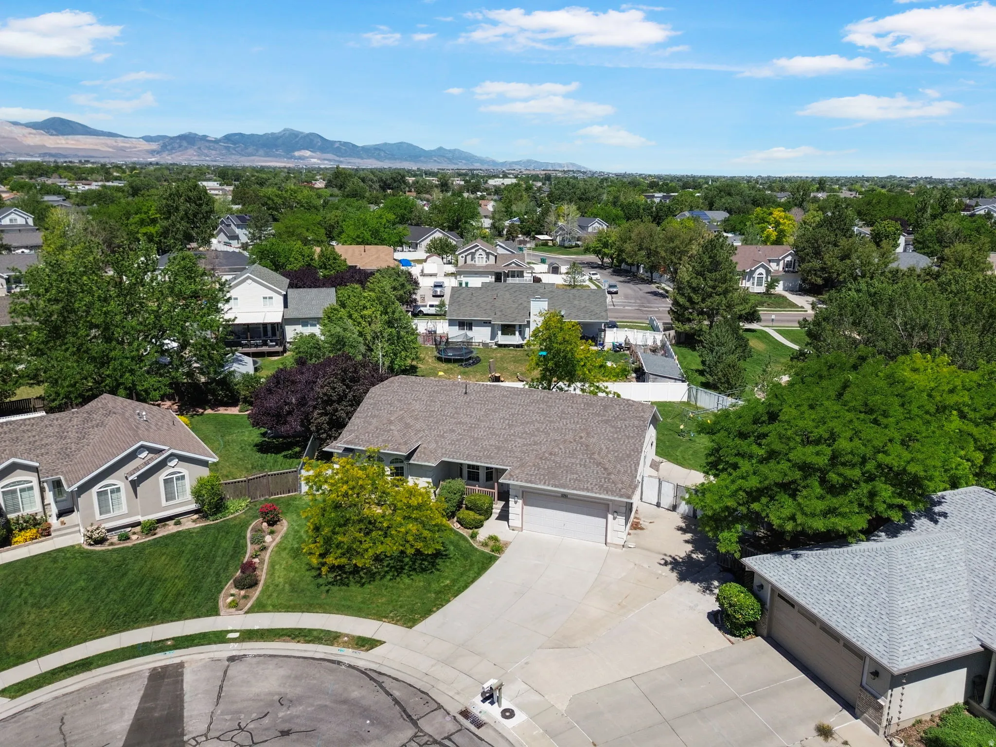 Residential property featuring a two-car garage, concrete driveway, and mature landscaping