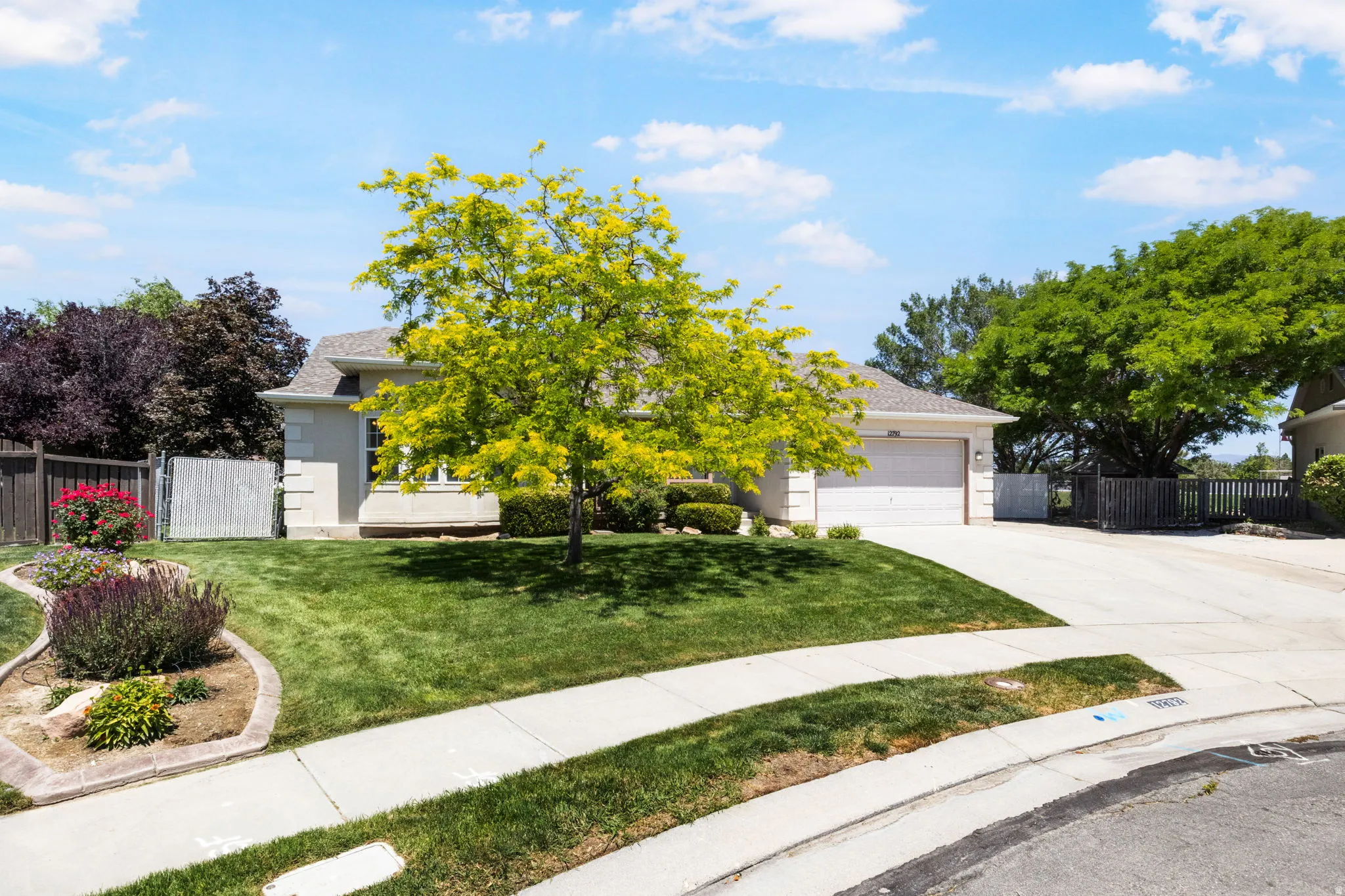 Single-story residence featuring a two-car garage, concrete driveway, and a well-maintained lawn