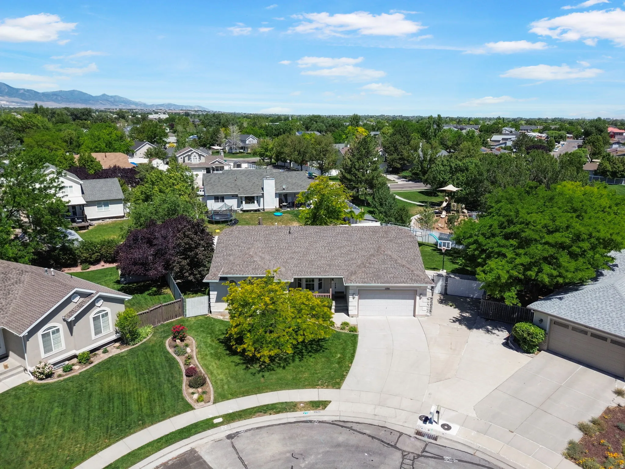 Ranch-style residence featuring an attached two-car garage, mature landscaping, and a concrete driveway